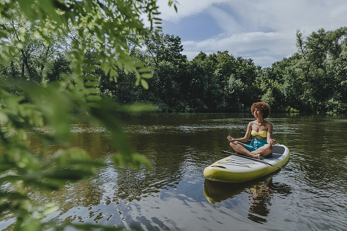 Woman meditating on paddleboard in lake