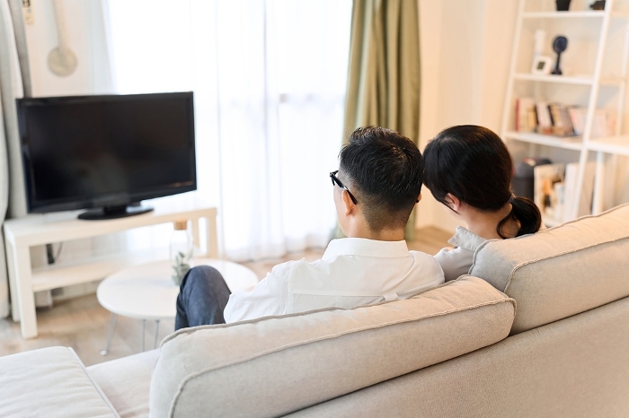 Asian couple watching TV in the living room