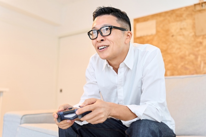 Asian man playing game in living room （Japanese / People)