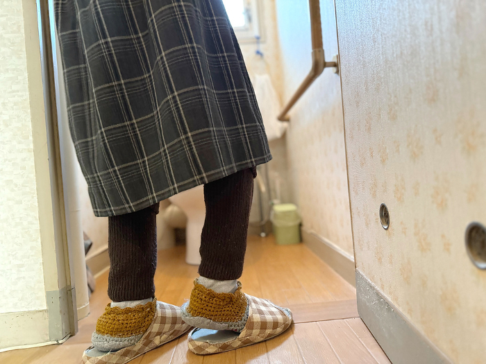 A woman's feet about to fall through a western style toilet door.