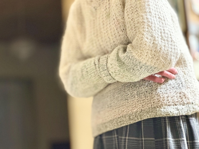 Elderly woman's hand with one hand inside the sleeve of her sweater.