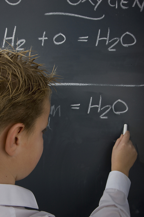 Back view of a school boy writing on a blackboard, by Ableimages