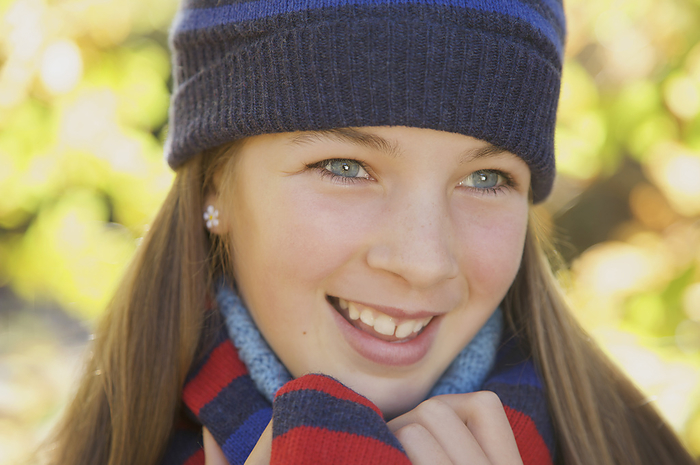 Smiling young girl wearing a woolly hat, by Jutta Klee
