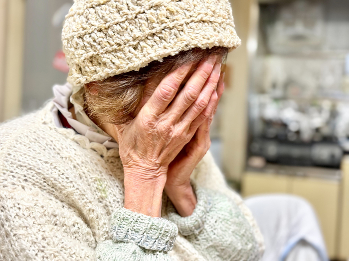 Elderly woman covering her face with her hands