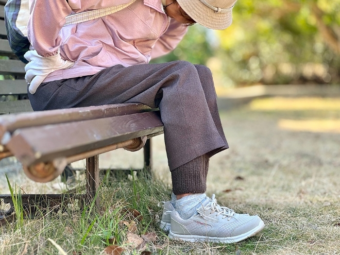 Elderly woman sitting on a bench holding her waist