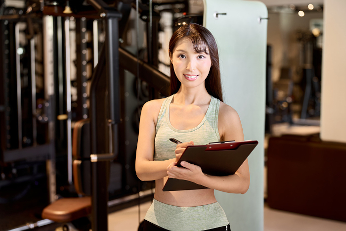 Japanese female personal trainer conducting a hearing at a fitness gym (People)