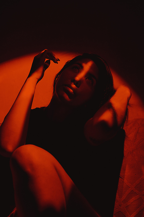 Portrait of a woman shot with red light and shadows on the face, by Cavan Images / Sergey Nepsha