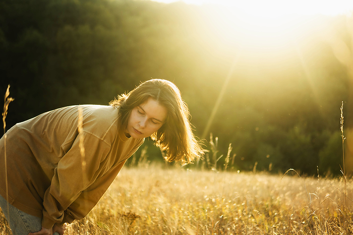 Beautiful portrait of a young stylish woman on sunset in nature, by Cavan Images / Inna Chernysh