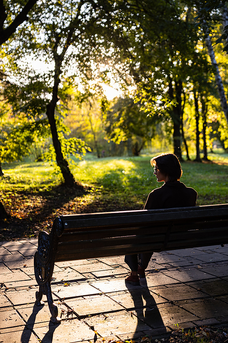 Young stylish woman with short hair in glasses sits on a park, by Cavan Images / Inna Maksymenko