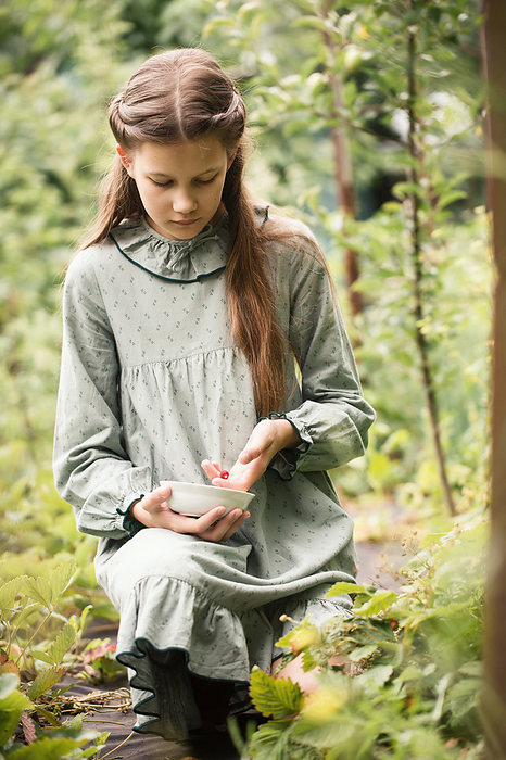 A teenage girl is picking strawberries, by Cavan Images / Iuliia Malivanchuk