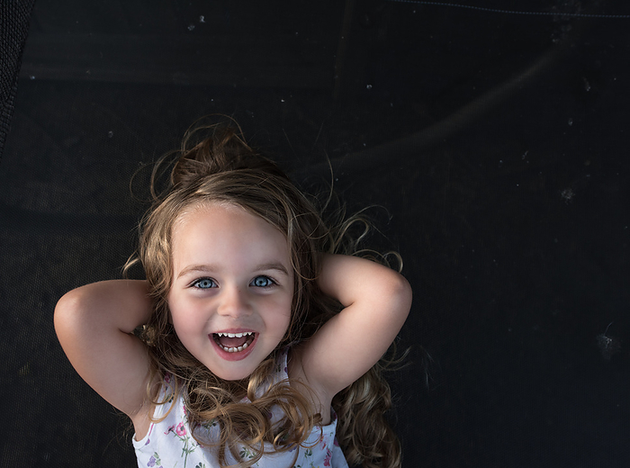 Beautiful toddler with curls laughing, by Cavan Images / Joy Faith