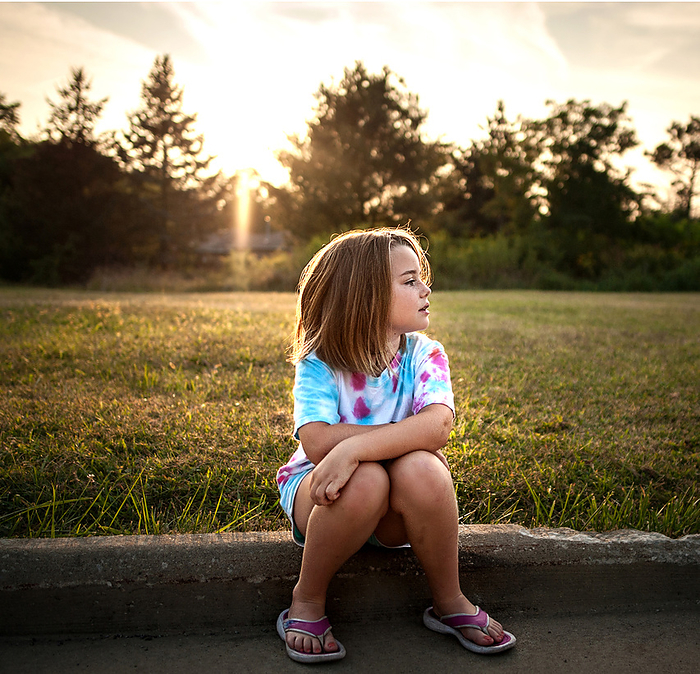 Beautiful young girl sitting outdoors in summer, by Cavan Images / Joy Faith