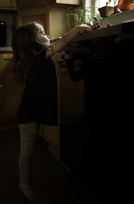 Little girl reaching for strawberries on kitchen counter, by Cavan Images / Joy Faith