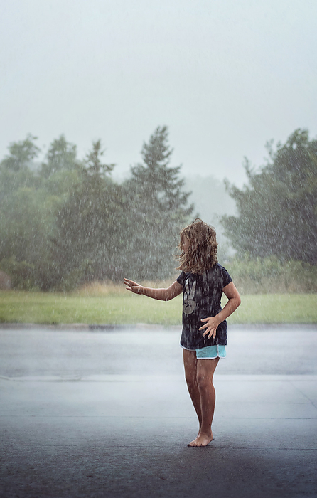 Young girl playing in the rain in summer, by Cavan Images / Joy Faith
