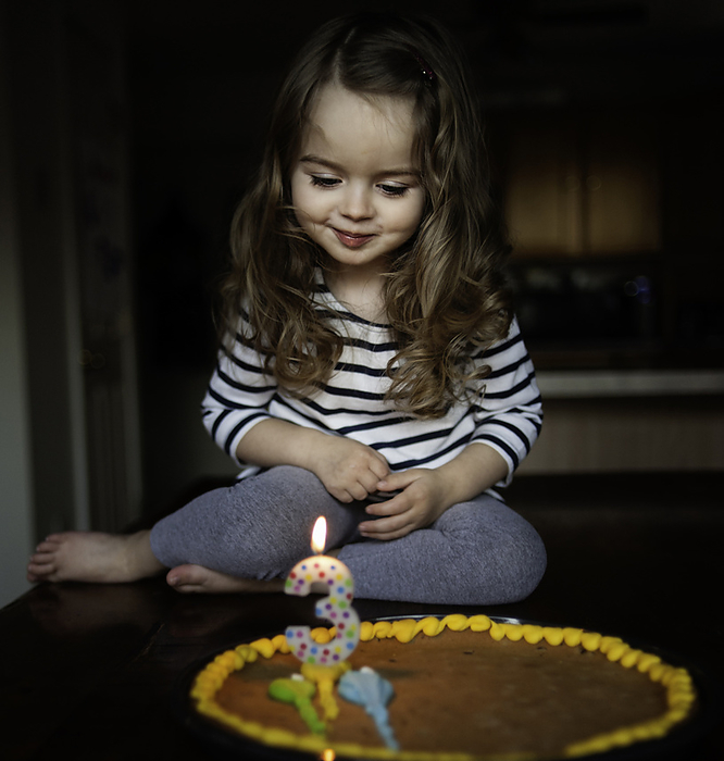 Beautiful little girl making wish on birthday candle, by Cavan Images / Joy Faith