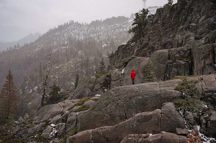 Wide view of person standing on trail on distant peak, by Cavan Images / Liz Celeste