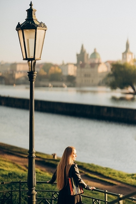 Young woman looking at panoramic city view in autumn Prague, by Cavan Images / Vetrana