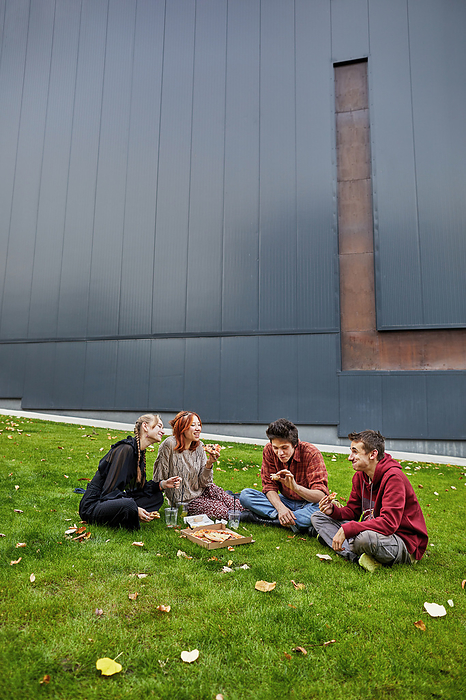 students eating pizza and laughing in the campus courtyard, by Cavan Images / Elena Perevalova