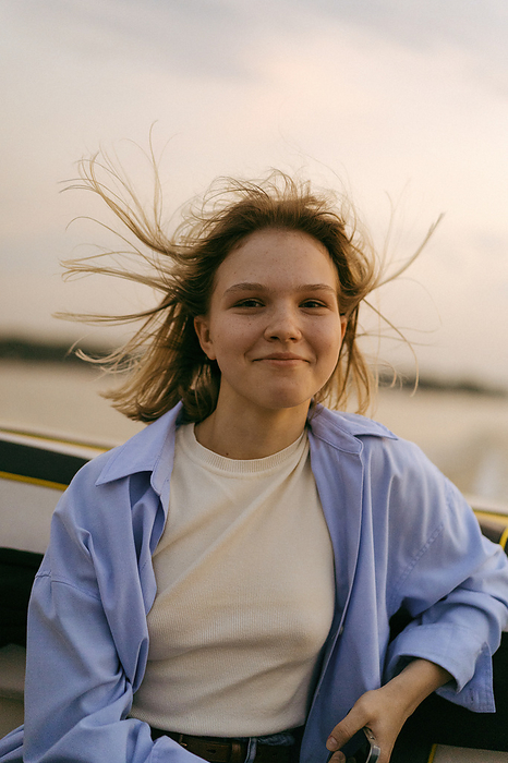 Young beautiful woman rides a speedboat on the lake. Wind in hair., by Cavan Images / Yuliya Kirayonak
