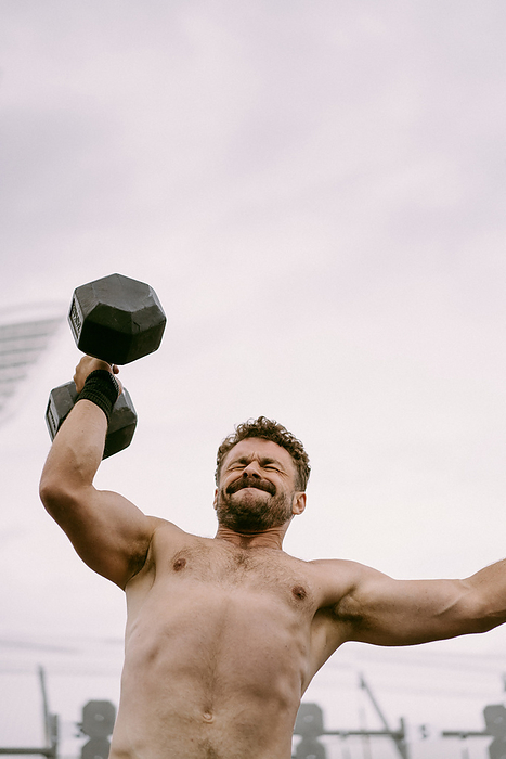 Men's CrossFit competition. A man lifts a dumbbell., by Cavan Images / Yuliya Kirayonak