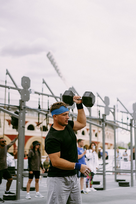 Men's CrossFit competition. Man with dumbbells., by Cavan Images / Yuliya Kirayonak