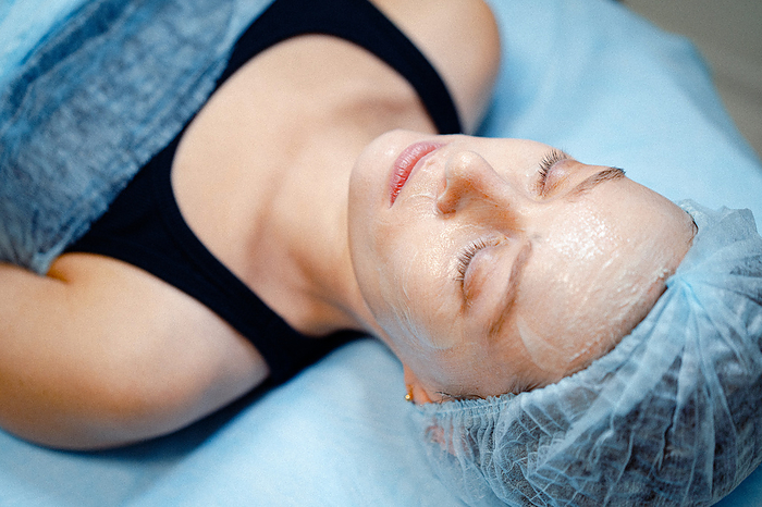 Woman facial treatment from beautician. Peeling, mask, skin care., by Cavan Images / Yuliya Kirayonak