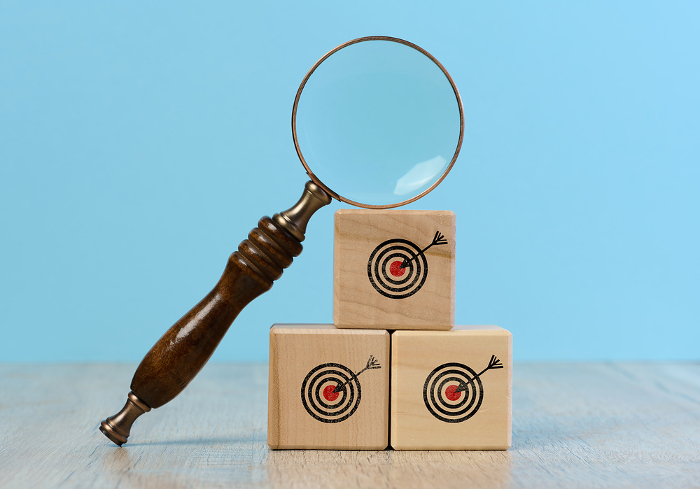 Wooden cubes with a drawn target and a magnifying glass on a blue background, symbolizing the search for truth Wooden cubes with a drawn target and a magnifying glass on a blue background, symbolizing the search for truth
