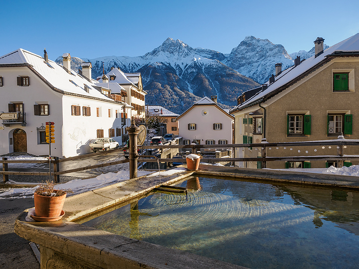 A plaza and fountain in the Alpine village of Sent in winter, Sent, Switzerland, Europe A plaza and fountain in the Alpine village of Sent in winter, Sent, Switzerland, Europe, by Melissa Kuhnell