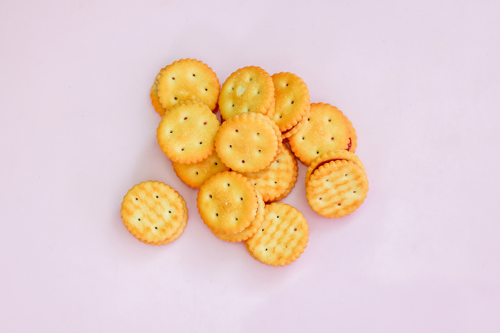 Cracker with strawberry jam on pink background