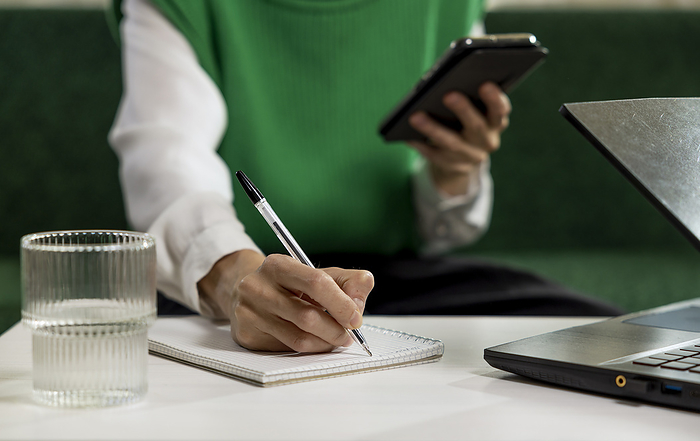 Freelancer taking notes from smart phone at home office