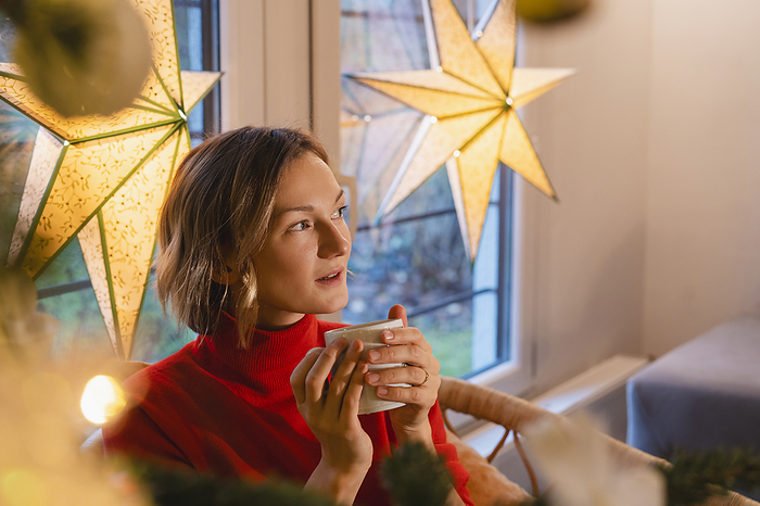 Thoughtful blond woman with coffee cup at home during Christmas
