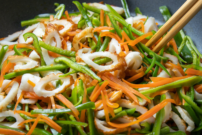 Pan-frying bamboo rings, bell peppers and carrots, cooking scene.