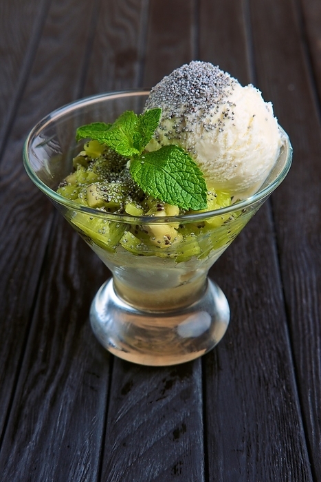 A cup of apple ice cream decorated with kiwi, mint leaves and poppy