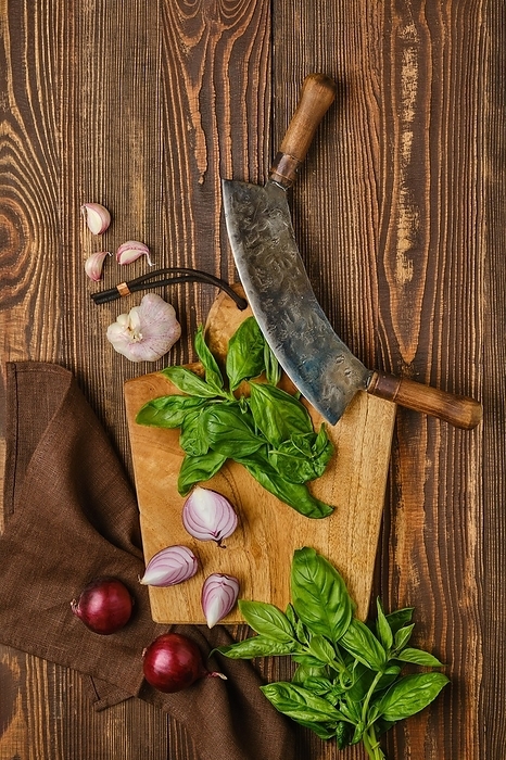 Preparation of simple rustic salad. Basil, onion and garlic on wooden cutting board