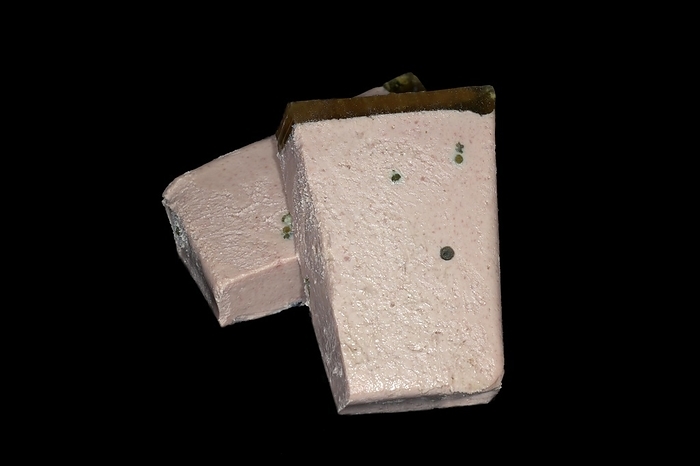 Halved liver pate with aspic and fresh green pepper, studio photography with black background
