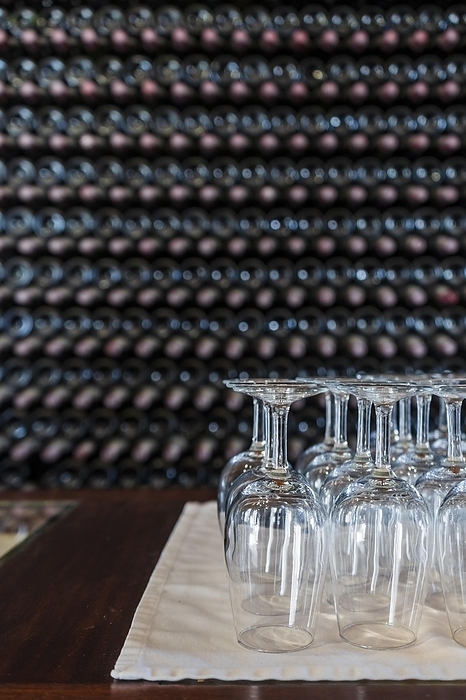 Empty wine glasses with many stacked bottles as a background, preparation to wine tasting in the winery of Lanzarote, Spain, Europe