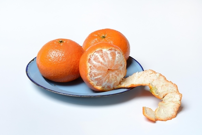 Clementines on plate, unpeeled and half peeled, white background, Germany, Europe