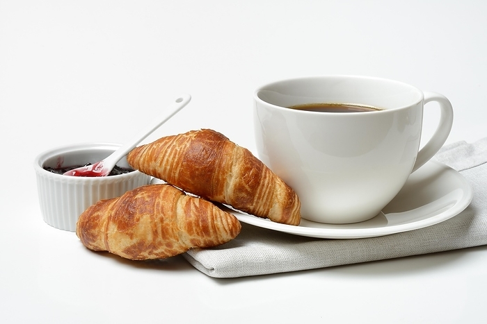 Two croissants with cup of coffee, jam in bowl