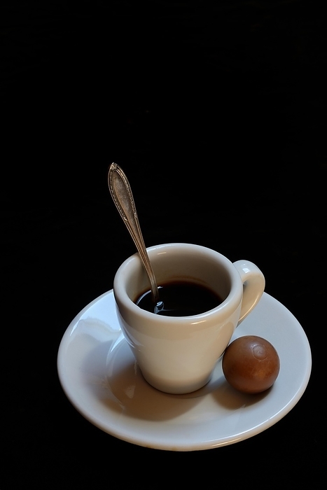 A cup of coffee and chocolate praline on a black background, espresso