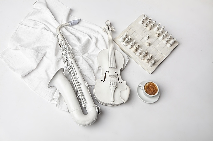 Saxophone, violin, chess and cup of coffee on a white background
