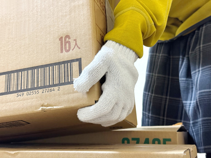 Close-up of a hand wearing military gloves lifting a piece of cardboard
