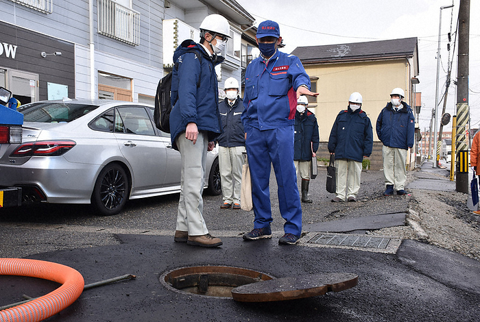 Mr. Taizo Yuasa, disaster assessment officer of the Ministry of Land, Infrastructure, Transport and Tourism, checking the damage inside a manhole. Mr. Taizo Yuasa, disaster assessment officer of the Ministry of Land, Infrastructure, Transport and Tourism  front right , checks the damage inside a manhole in Nishi Ward, Niigata City at 3:21 p.m. on January 25, 2024.