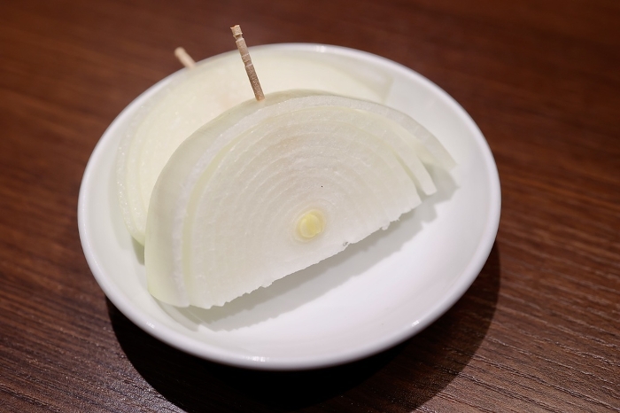 Half-moon sliced raw onion stuck in a toothpick