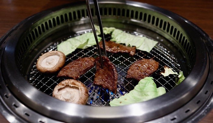 Grilling cabbage, shiitake mushrooms, and beef on a net at a barbecue restaurant