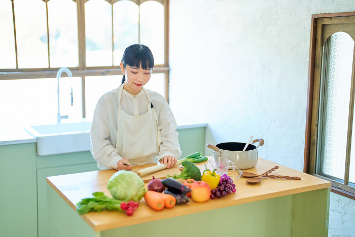 Young Japanese woman cutting food with a kitchen knife (People)