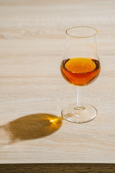 Glass of cognac on a table in a bright sunny day, by Aleksei Isachenko