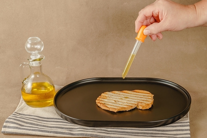 Woman pours olive oil on toast with an dropper because of excessive oil prices, by jose hernandez antona