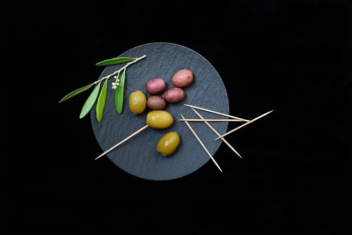 Green and black olives with toothpick on black plate, Germany, Europe, by Jürgen Pfeiffer