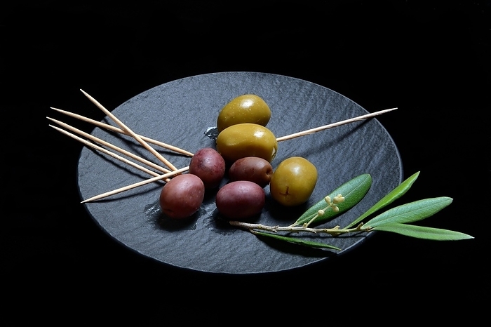Black and green olives with toothpick on black plate, Germany, Europe, by Jürgen Pfeiffer