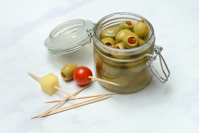 Green olives in glass and on toothpicks with tomato and cheese cubes, by Jürgen Pfeiffer